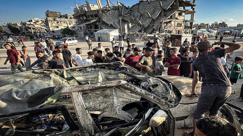 مواطنون يتجمعون في موقع غارة جوية إسرائيلية استهدفت مركبة في حي تل الهوى بمدينة غزة