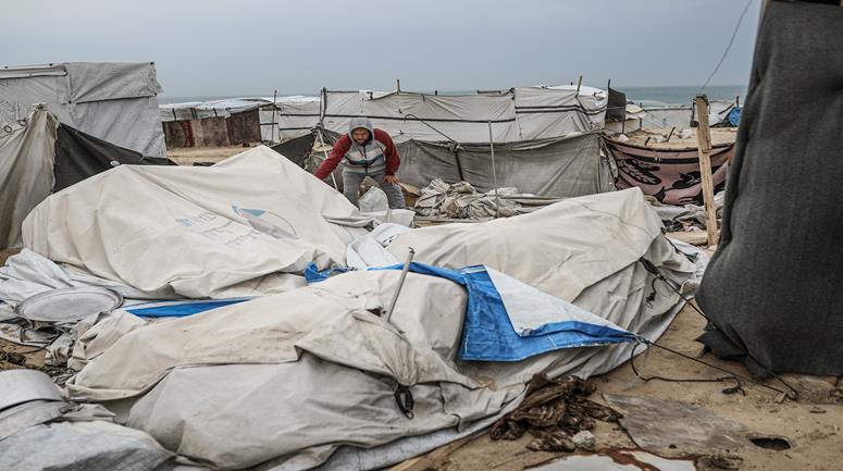  نازحون يتفقدون خيامهم بعد أن تضررت جراء عاصفة هوائية قوية ضربت مخيماً للنازحين في المحافظة الوسطى بقطاع غزة