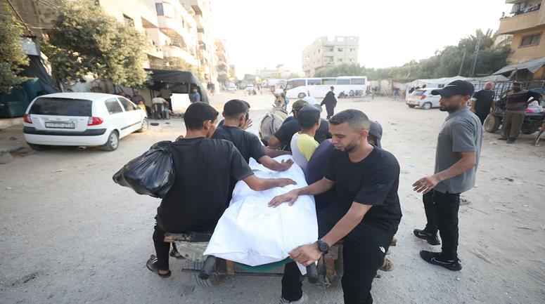 مواطنون ينقلون جثمان شهيد ومصاب في غارة إسرائيلية، إلى مستشفى العودة في مخيم النصيرات وسط قطاع غزة