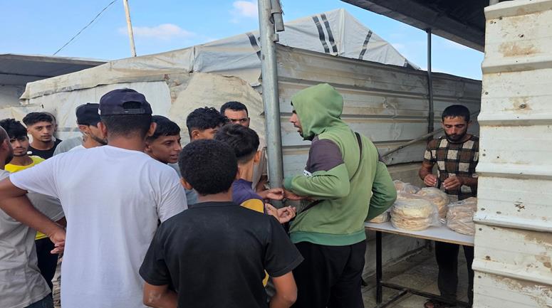 مواطنون يصطفون للحصول على الخبز من نقطة بيع بخان يونس جنوب قطاع غزة، وسط تفاقم الأزمة الإنسانية وتراجع تمويل برامج الغذاء والمساعدات
