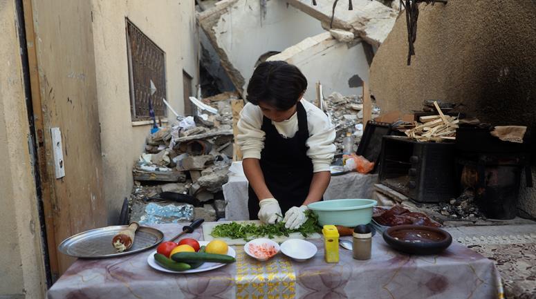 الطفل ياسر عياد (14 عاماً) يمارس موهبته في طهو الطعام فوق نارٍ بدائية إلى جانب ركام منزل عائلته المدمّر في مدينة غزة، في مشهد يعكس واقع الحياة اليومية تحت وطأة الدمار في ظل ظروف إنسانية متفاقمة