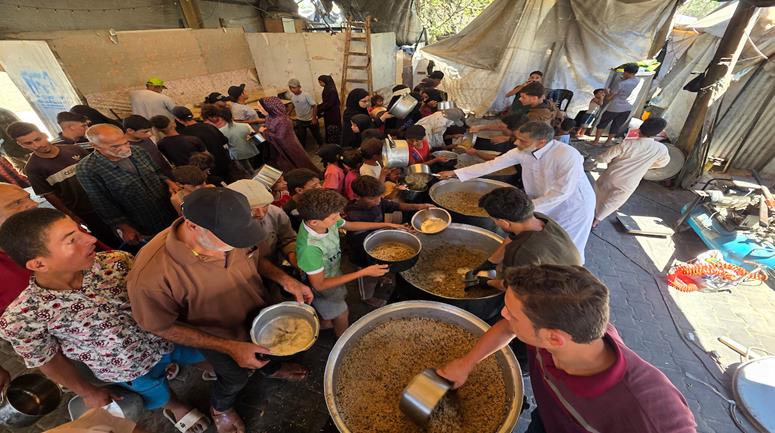 نازحون يتلقون وجبات طعام مطهية يوزعها مطبخ خيري في منطقة المواصي غرب خان يونس