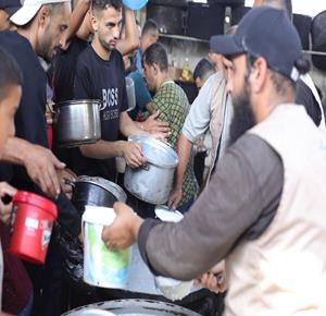 نازحون يتجمعون للحصول على وجبات طعام من تكية خيرية في مخيم النصيرات وسط قطاع غزة