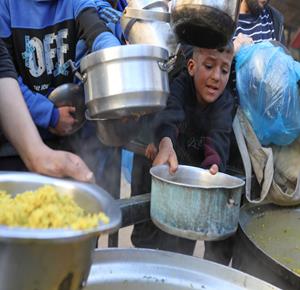 نازحون يتجمّعون للحصول على وجبة الإفطار في شهر رمضان من تكية خيرية في مخيم النصيرات وسط قطاع غزة