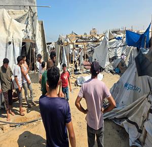 مواطنون يتفقدون آثار الدمار الذي خلفه القصف الاسرائيلي على خيمة تؤوي نازحين في منطقة المواصي بخان يونس