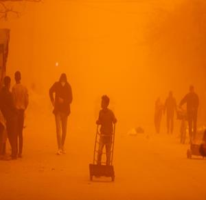 مواطنون يسيرون وسط عاصفة رملية في مخيم للنازحين بخان يونس جنوب قطاع غزة