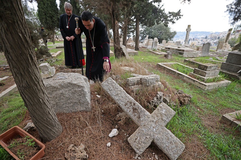 رئيس الأساقفة الأنغليكاني في القدس المطران حسام نعوم يتفقد آثار الاعتداء على المقبرة (تصوير: أ ف ب)