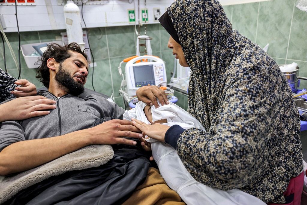 مواطن جريح يودّع نجله الشهيد بمستشفى في رفح جنوب قطاع غزة (تصوير: أ ف ب)