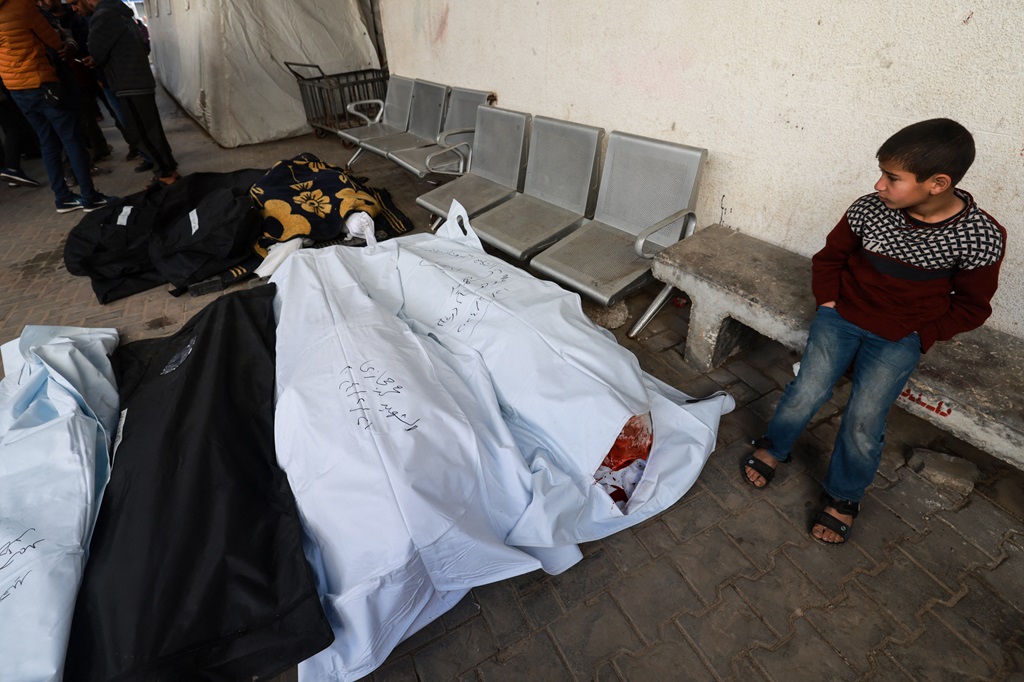 طفل ينظر إلى جثامين شهداء في ساحة مستشفى الشهيد أبو يوسف النجار في رفح جنوب قطاع غزة (أ ف ب)